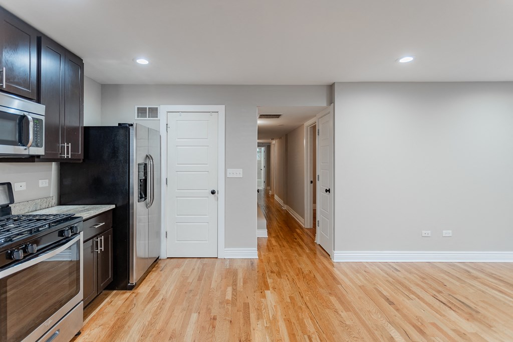 a renovated kitchen with wood floors and black appliances and a white door