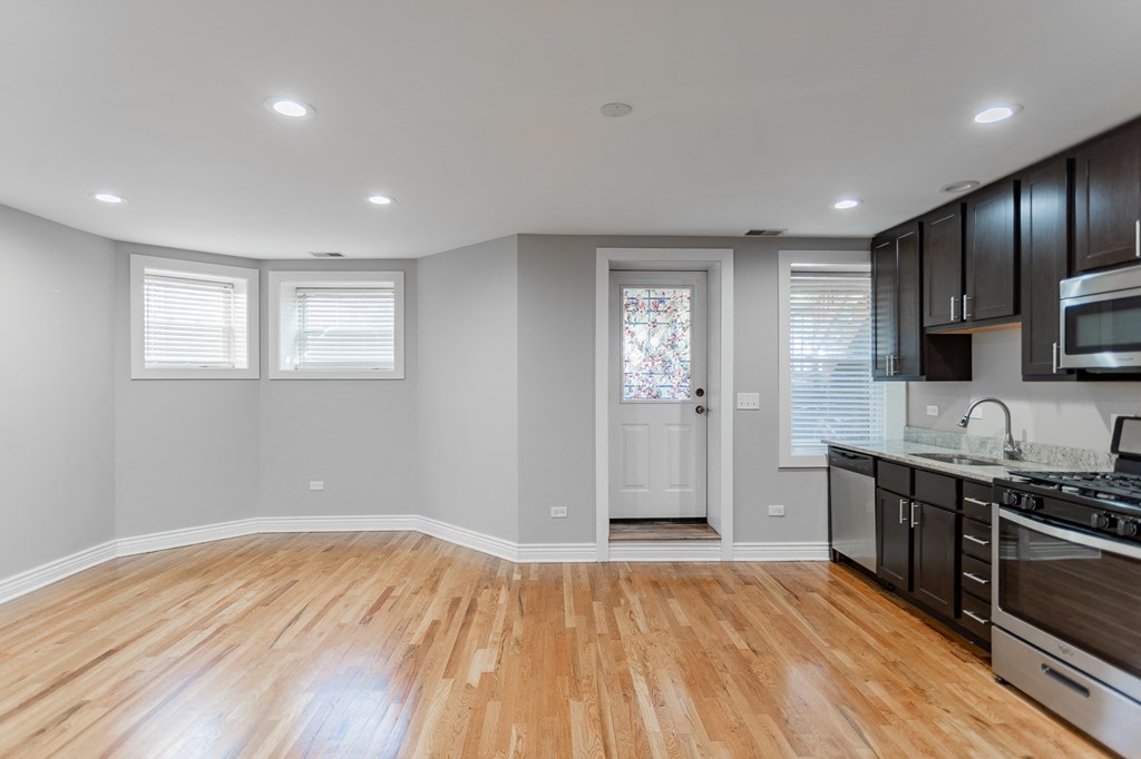an empty kitchen with wood floors and black cabinets