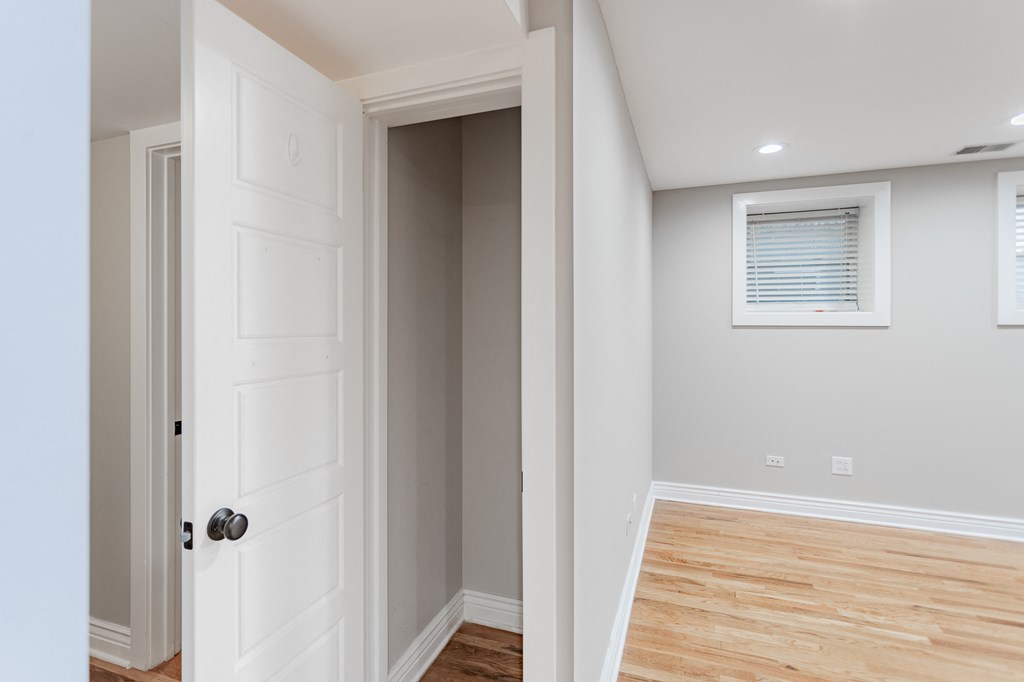a room with a white door and a hallway with a wood floor