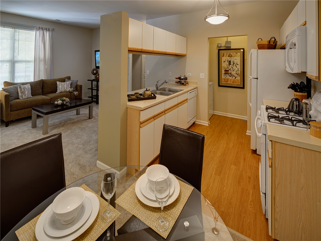 a dining room table with plates on it in front of a kitchen and living room