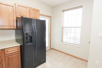 Side by side black fridge in kitchen with warm brown cabinets