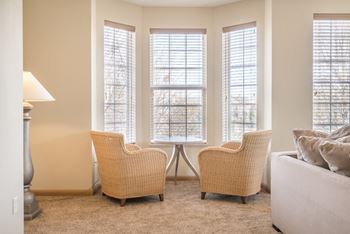 Living room bay window with horizontal blinds and seating area positioned around it