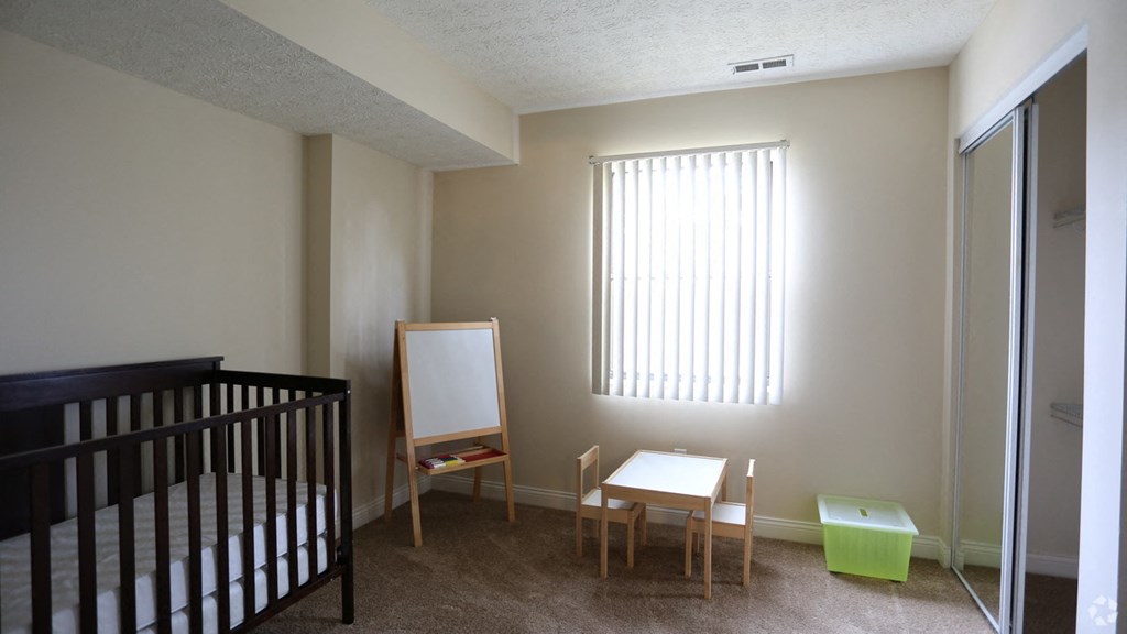 an empty room with a crib and a table and a mirror