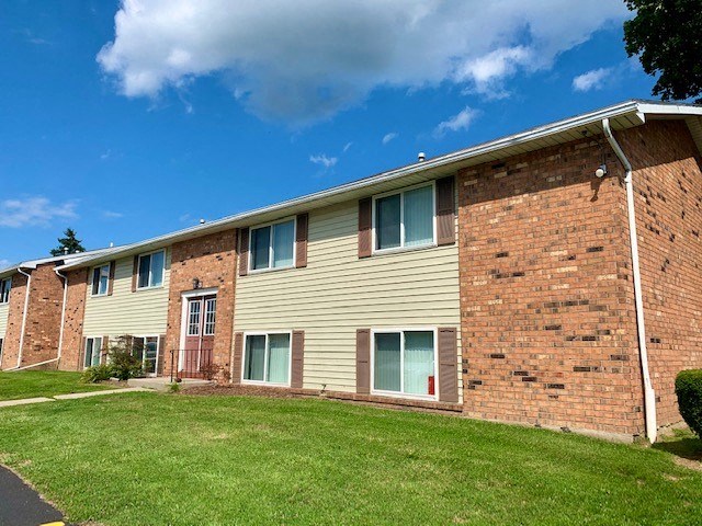 a brick apartment building with a green lawn