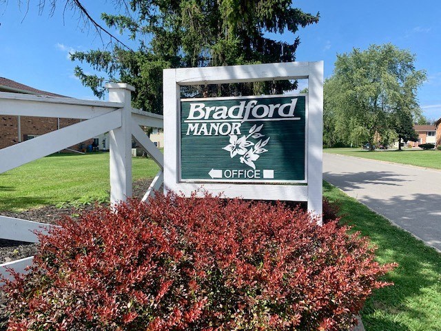 a sign for the manor office on the side of a street