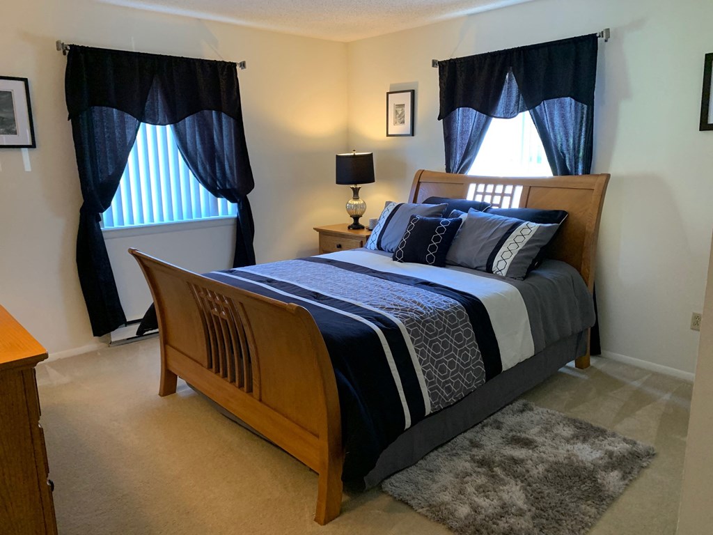 a bedroom with a bed and two windows with blue curtains