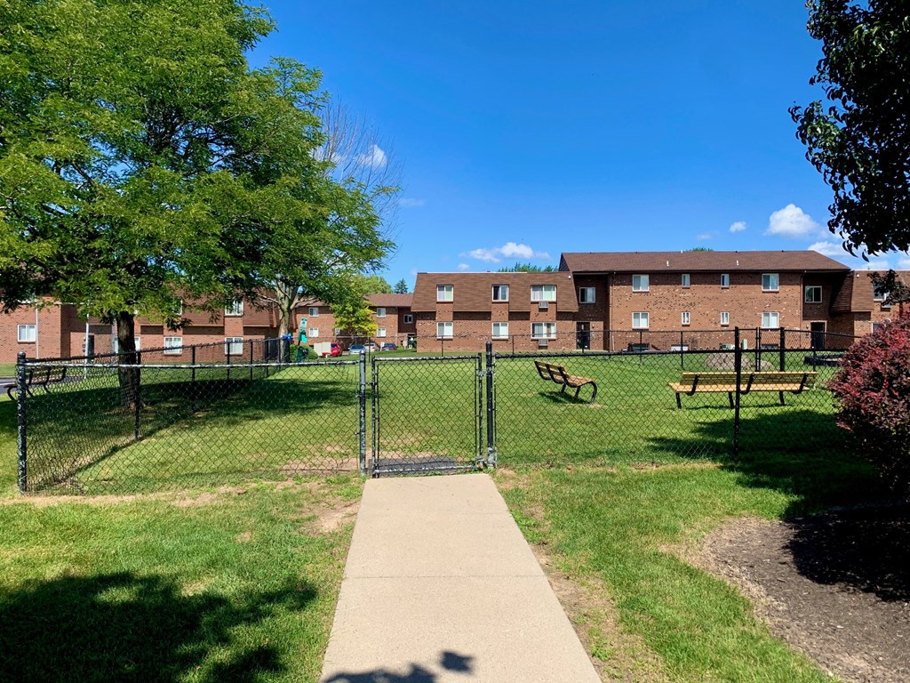 a fenced in dog park in front of a brick building