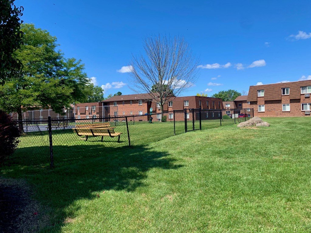 a fenced in dog park in front of a brick building