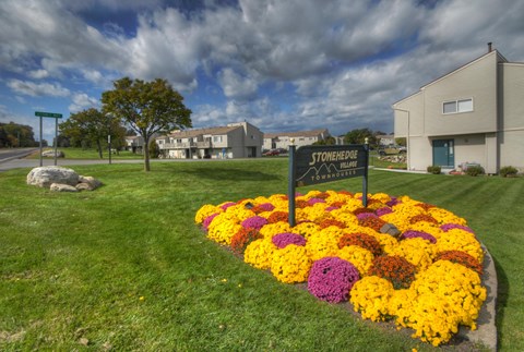 Front Sign with Flowers and Green Lawn at Stone Hedge Village Townhouses, Farmington, NY