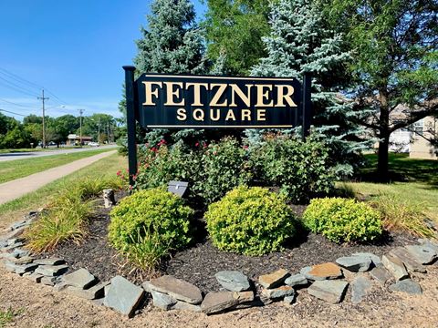 a sign for fetzner square in front of a landscaped garden