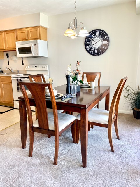 a dining room table with chairs and a clock on the wall