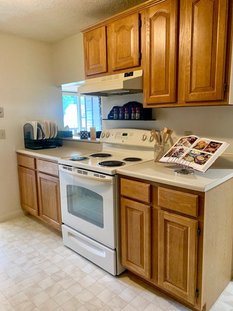 a kitchen with a stove and cabinets and a magazine on the counter