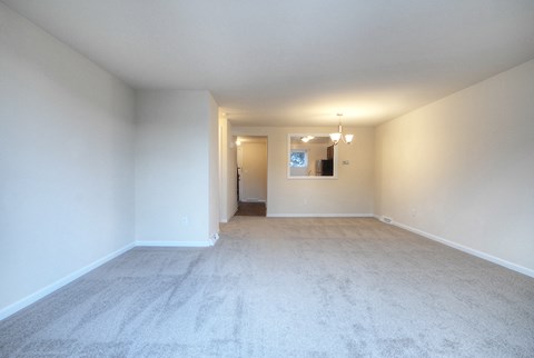 an empty living room with white walls and carpet