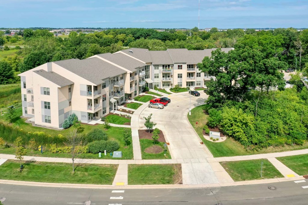 an aerial view of an apartment building with a parking lot and trees