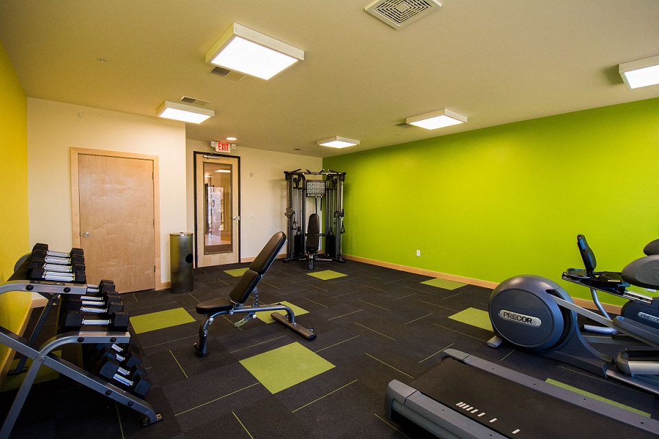 a gym with exercise equipment and a green wall