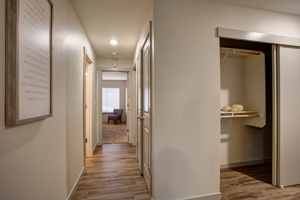 a hallway with a door to a closet and a living room