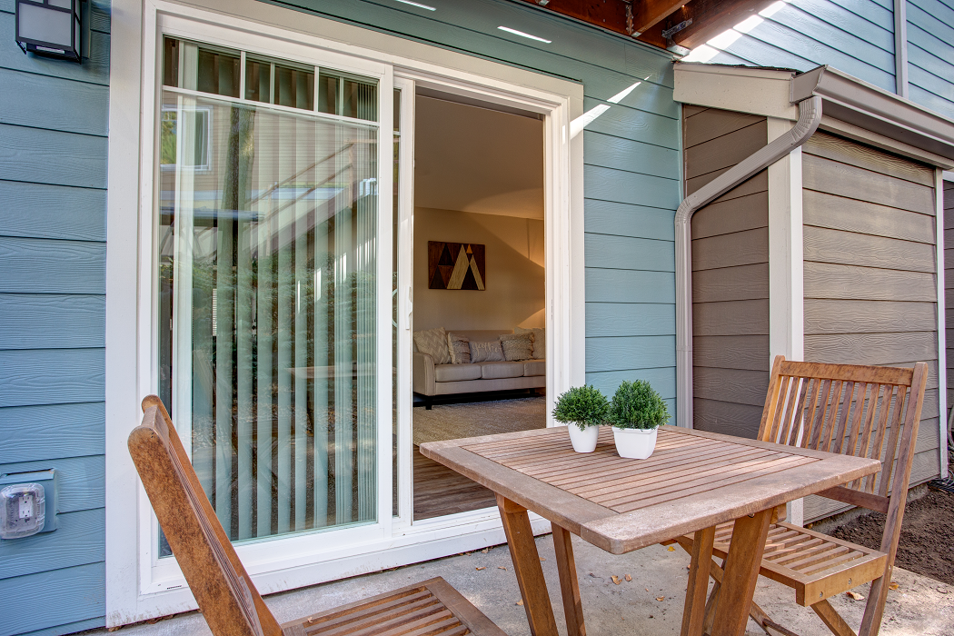 a patio with a wooden table and chairs and a sliding glass door