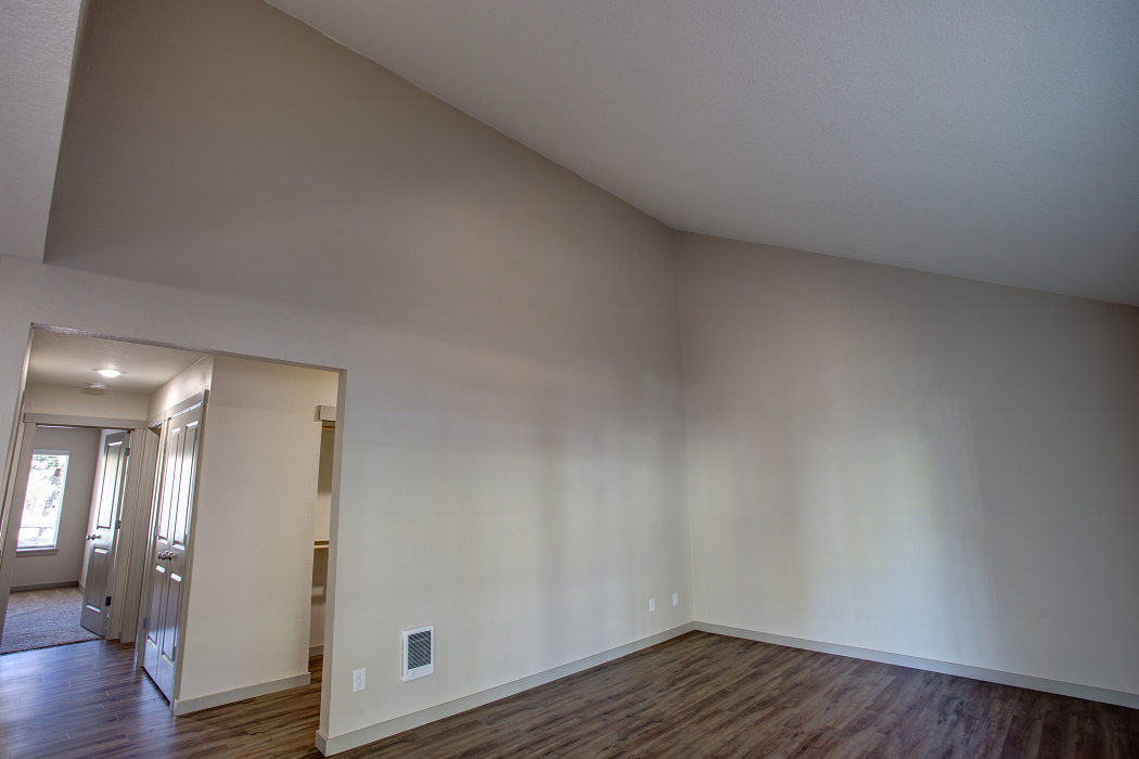 an empty living room with wood floors and white walls