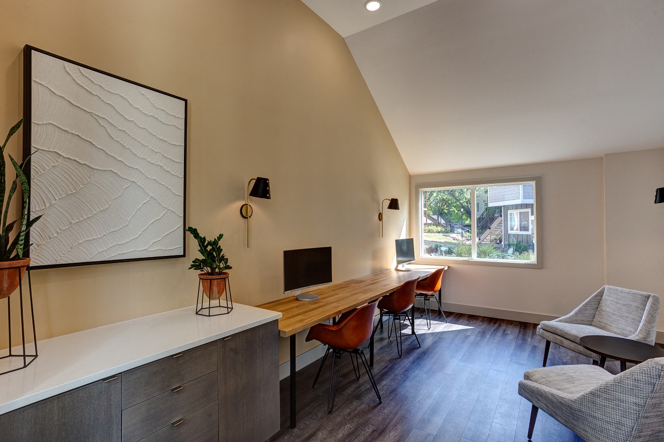 a home office with a desk and chairs and a window
