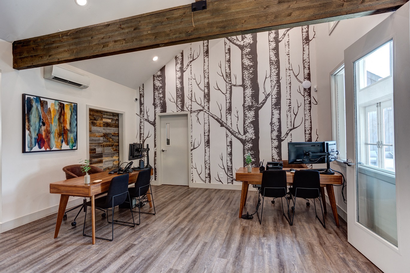 an office with a desk and chairs and a wall mural of trees