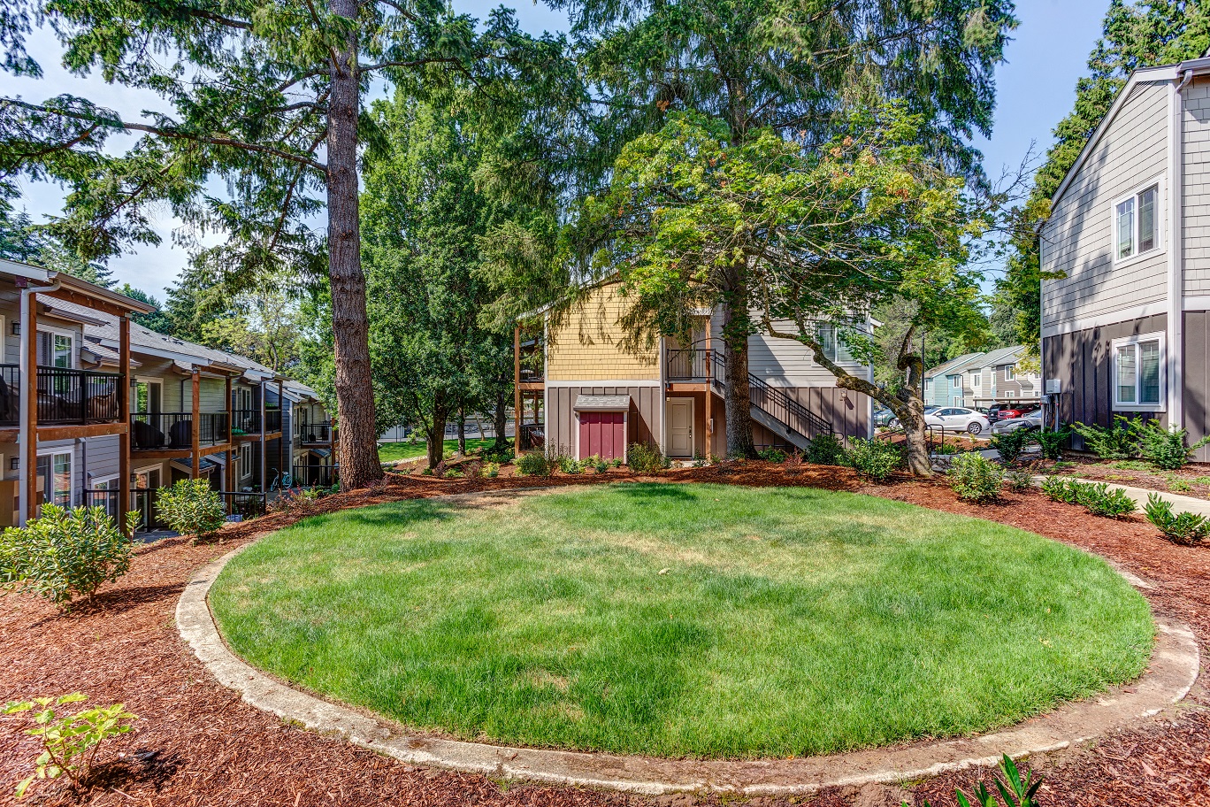 a circle of grass in front of a house with trees