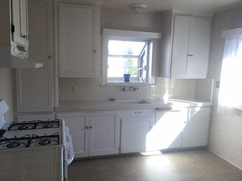 a small kitchen with white cabinets and a window