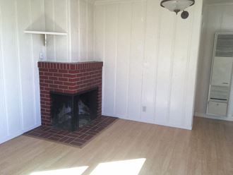 the living room has a brick fireplace and a wooden floor
