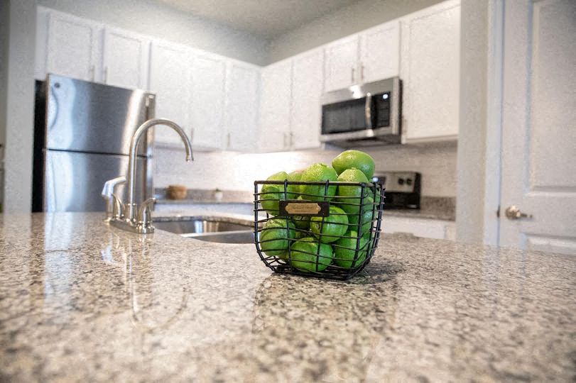 A kitchen counter with a bowl of green apples on it.