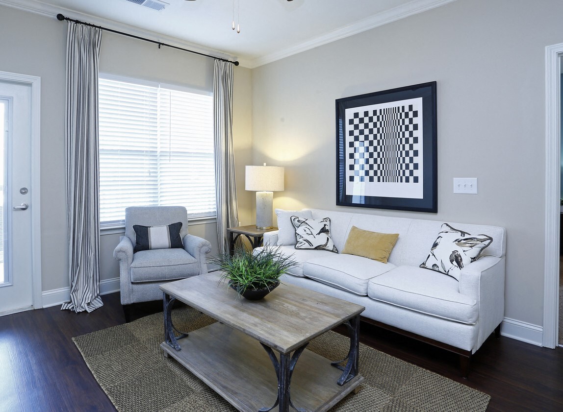 A living room with a white couch, a grey armchair, a wooden coffee table, and a painting on the wall.