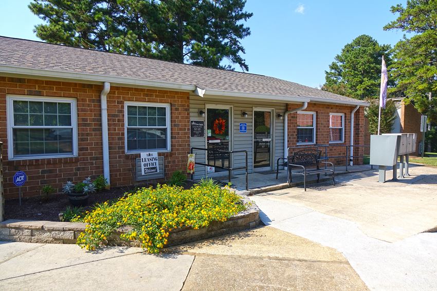 the front of a brick building with a porch and a sidewalk