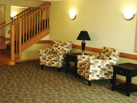 Two chairs and a table with a lamp on it.