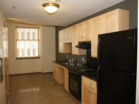an empty kitchen with black appliances and wood cabinets