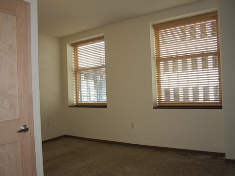 an empty room with two windows and a door