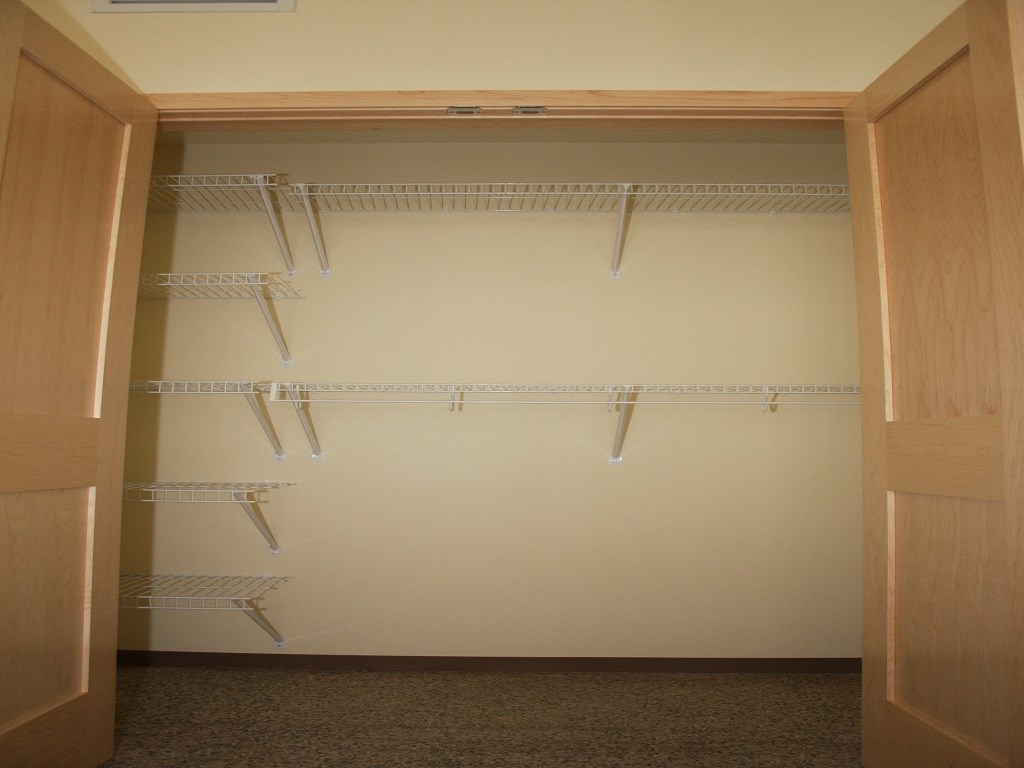 a walk in closet with shelves and a white wall
