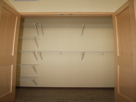 a walk in closet with shelves and a white wall