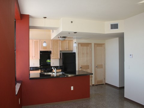 an empty kitchen with a red wall and a black counter top