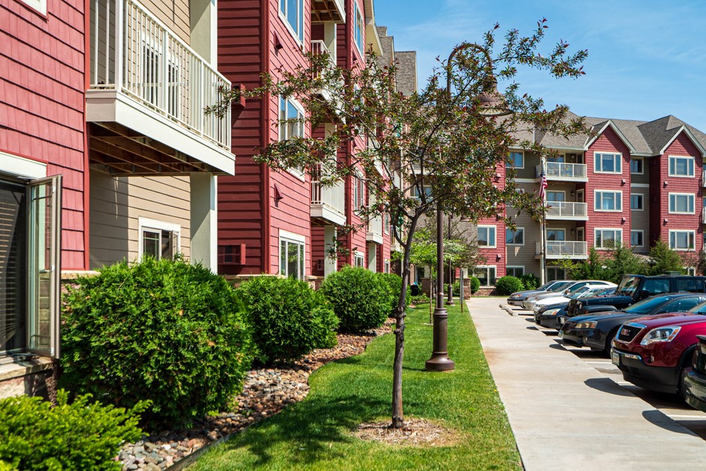 a row of red apartment buildings with cars parked in front of them