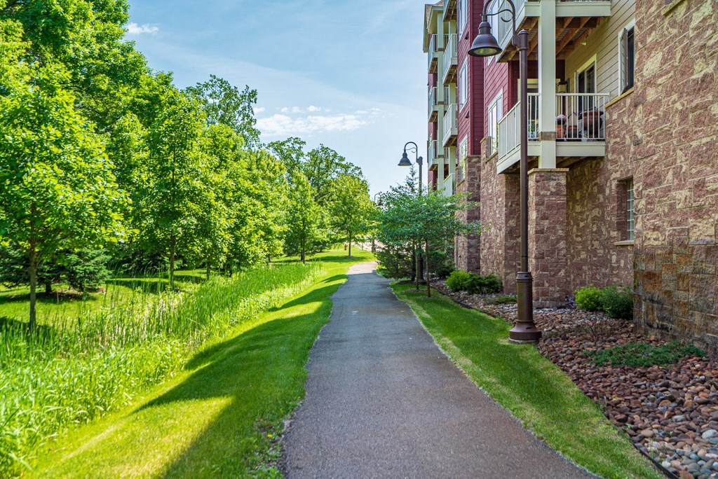 a sidewalk in front of a building with grass and trees