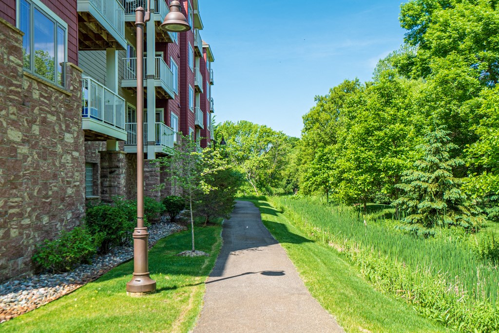 a sidewalk in front of a building with grass and trees