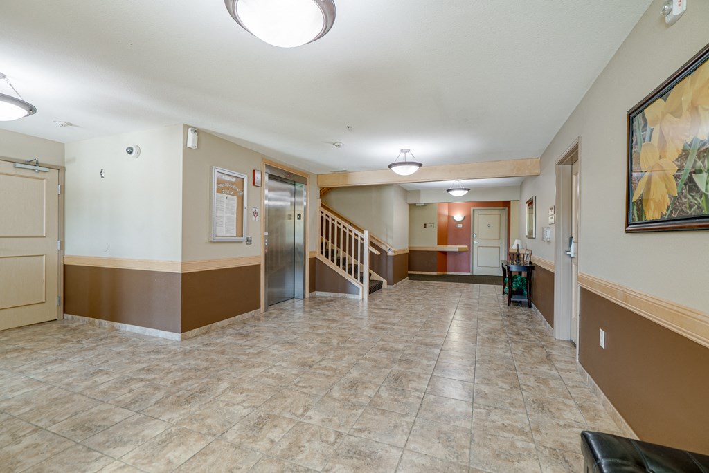 a lobby with a staircase and a hall way with a door and a painting