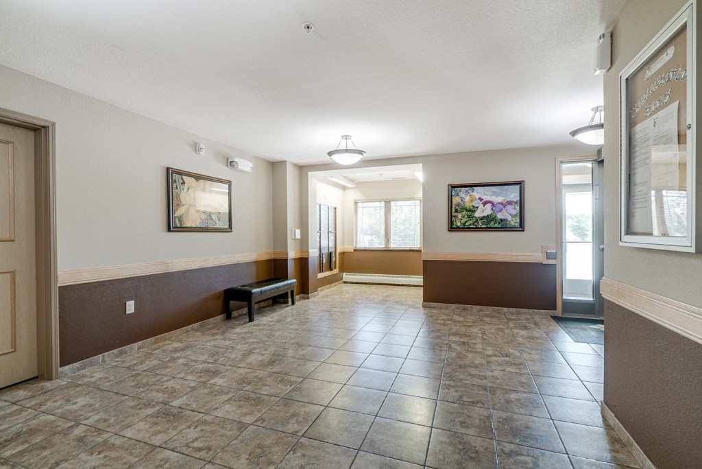 a large lobby with tile flooring and a door to a hallway