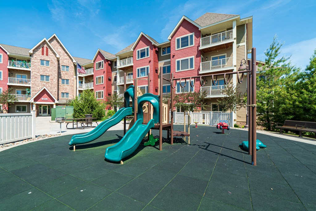 an outdoor playground with slides in front of an apartment building