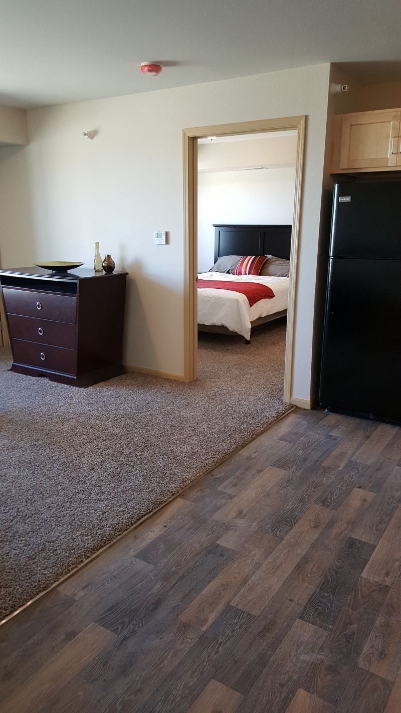 a bedroom with a black refrigerator and a bed