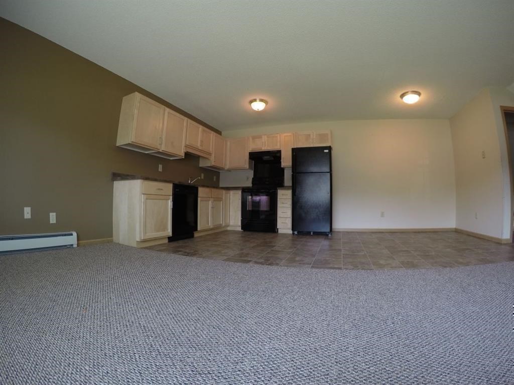 a empty living room with a kitchen and