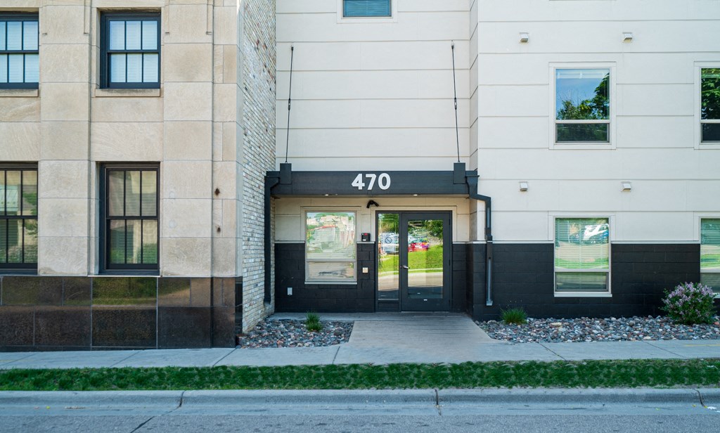 the front of a building with doors and a sidewalk