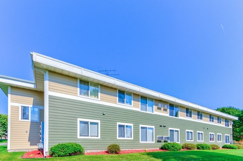 an apartment building with green siding and a blue sky