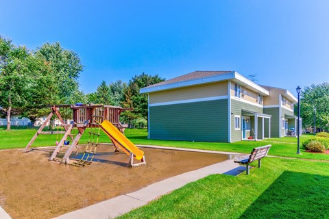 a playground with a swing set in front of a house