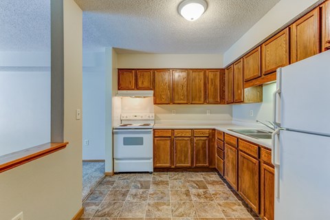 an empty kitchen with wooden cabinets and white appliances