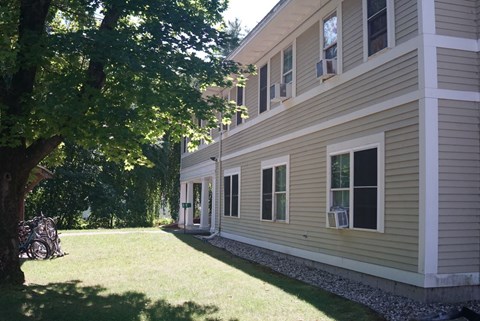 A house with a green lawn and a tree in front.