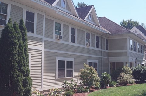 A grey house with a brown roof and white trim.
